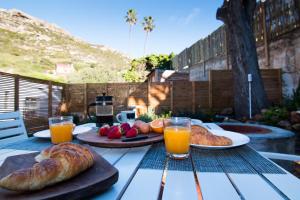 a table with two plates of bread and orange juice at Spacious and light Kalk Bay Garden Apartment in Kalk Bay