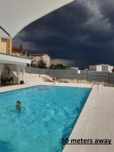 un hombre en una piscina bajo un cielo nublado en Pansion Ivan, en Međugorje