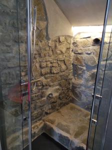 a bathroom with a shower with a stone wall at KISS from CILENTO in Celso