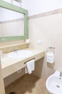 uma casa de banho com um lavatório, um espelho e um WC. em Hotel Marhava em Conil de la Frontera