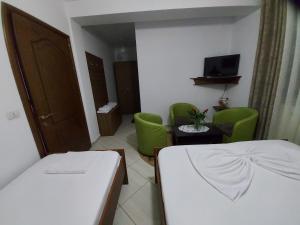 a room with a bed and chairs and a television at HOTEL KALEMI in Çorovodë