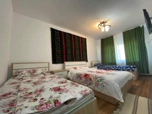 two beds in a bedroom with green curtains at Agropensiune Turistica Maria in Isverna