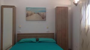 a bedroom with a green bed and a picture on the wall at Villa Ines in Jezera
