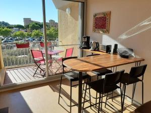 a room with a table and chairs and a balcony at Entre port et village in Gruissan