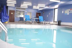 uma piscina com cadeiras azuis e uma mesa num edifício em Days Inn by Wyndham Sioux City em Sioux City