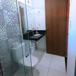 a bathroom with a toilet and a glass shower at Flats Maui in Barra Grande