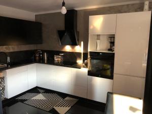 uma cozinha com armários brancos e electrodomésticos pretos em Apartament Moniuszki em Kędzierzyn-Koźle