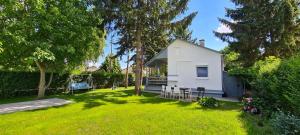 una pequeña casa blanca en un patio con árboles en Világos Kert Balatonvilágos Chill House, en Balatonvilágos