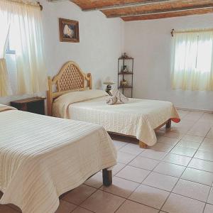 a bedroom with two beds with white sheets at Manzano B&B in Guanajuato