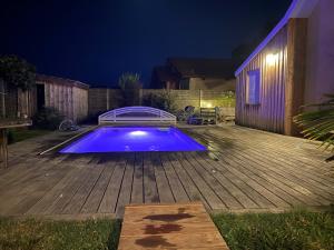 a swimming pool on a wooden deck at night at L'annexe in Le Teich