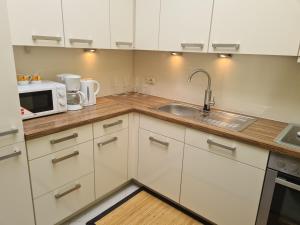 uma cozinha com armários brancos, um lavatório e um micro-ondas em FeWo Reiswich em Cochem