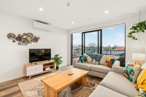 a living room with a couch and a tv at Barbadoes Beauty - Christchurch Holiday Apartment in Christchurch