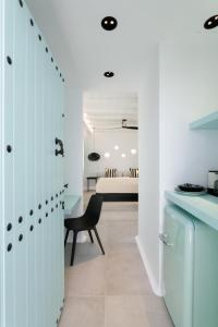 a kitchen with white cabinets and a black chair at Majo Suites Hotel in Agia Anna Naxos