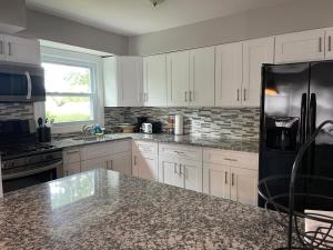 a kitchen with white cabinets and a black refrigerator at The Best of the Jersey Shore #airbnb in Long Branch