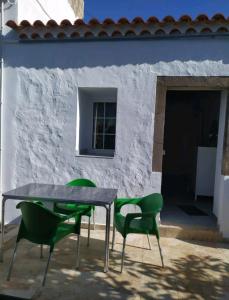 a table and four green chairs in front of a building at Moya, Senderos y naturaleza in Moya