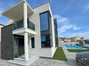 a white house with a pool and a car at Villa Eureka in Vodice