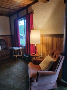 a living room with a chair and a lamp at Little River Inn Motel in Leon