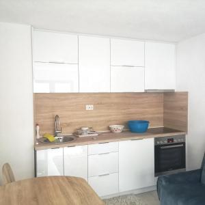 a kitchen with white cabinets and a sink and a table at Family apartment with garden in Sarajevo