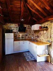 a kitchen with white appliances and a stone wall at El Cuarto in Suarbol