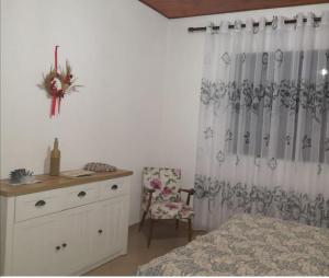 a bedroom with a bed and a chair and a curtain at Private House Durres in Durrës