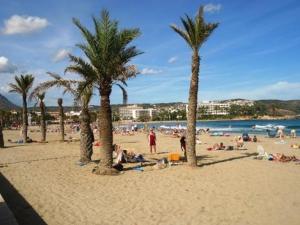 a group of people on a beach with palm trees at La Casita Bonita - 30m from the Arenal Beach - Private Parking in Jávea