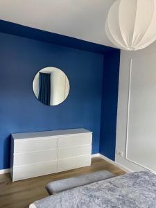 a blue bedroom with a white dresser and a mirror at Apartament LEA in Międzywodzie