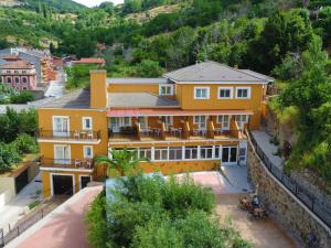 a yellow house with a courtyard in front of a mountain at Hotel Rural El Molino in Baños de Montemayor