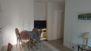 a dining room with a table and chairs and a television at Guarujá Pitangueiras Flat Capitania Varam in Guarujá
