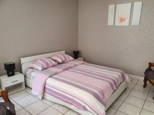 a bedroom with a bed with a pink and purple striped blanket at Meublés B-D in Bains-les-Bains