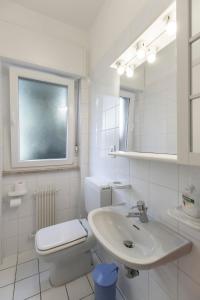 biała łazienka z toaletą i umywalką w obiekcie Apartament Kormorano w mieście Malcesine