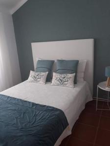 een slaapkamer met een groot bed met 2 kussens bij Casas Duarte in Nazaré