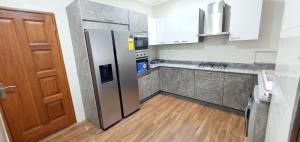 a kitchen with a stainless steel refrigerator and wooden floors at Mama Jane's Villa in Kasanwere