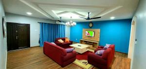 sala de estar con 2 sillas rojas y TV en Mama Jane's Villa en Akim Oda