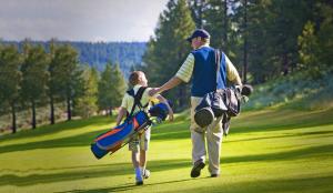 a man and a boy walking on a golf course at Modern Hotel-Style Studio - Timber Creek Lodge #210 Hotel Room in Truckee