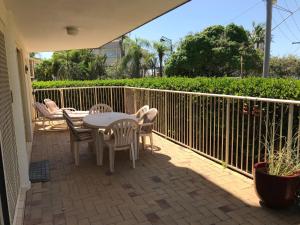 eine Terrasse mit einem Tisch, Stühlen und einem Zaun in der Unterkunft Kings Way Apartments in Caloundra