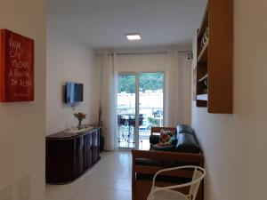 ein Wohnzimmer mit Sofa und Glasschiebetür in der Unterkunft Ótimo Apartamento Ubatuba in Ubatuba