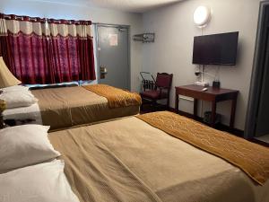 a hotel room with two beds and a desk and a television at Liberty Inn in Bowmanville