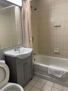 a bathroom with a sink and a tub and a toilet at Liberty Inn in Bowmanville