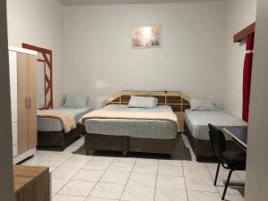 a room with three beds and a chair in it at Hotel Carrão in Sao Paulo +62 photos