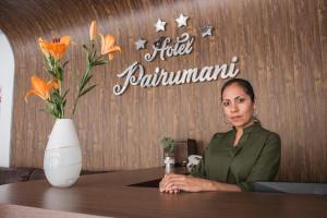 a woman sitting at a table with a vase of flowers at Hotel Pairumani in Cochabamba