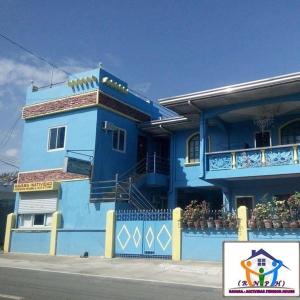 a blue building with a balcony on a street at RAVARA NATIVIDAD PENSION HOUSE in Alaminos