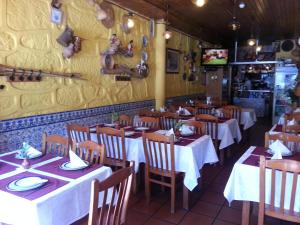 restauracja ze stołami i krzesłami oraz żółtą ścianą w obiekcie Caldeira Guest House w Porto