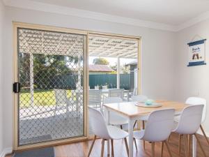 comedor con puerta de cristal con mesa y sillas en 9 Breckenridge Street, en Forster 4 fotos más