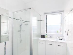 Un baño blanco con ducha y lavabo. en 9 Breckenridge Street, en Forster