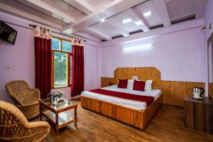 Habitación de hotel con cama y silla en Mountain Dew Guest House, en Manali