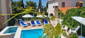 a swimming pool with chairs and umbrellas next to a building at Apartments Villa Natali - Heating Pool in Trogir