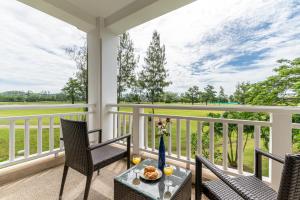 a porch with chairs and a table with a vase on it at Allamanda Laguna Phuket by RESAVA in Bang Tao Beach