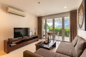 un soggiorno con divano e TV di The Park Surin Serviced Apartments a Surin Beach