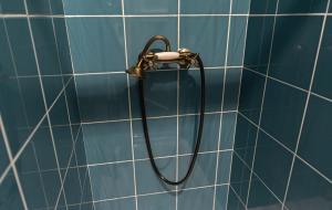 a shower head on a blue tiled bathroom wall at Ninho @ Francos in Porto