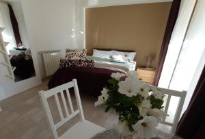 um pequeno quarto com uma cama e uma mesa com flores em B&B Casa Althea em Milo